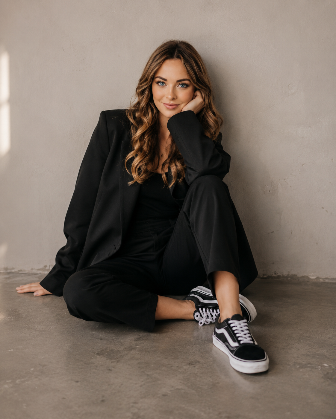 Mieke, founder of Rocket & Bloom, sitting on a concrete floor in a black suit and sneakers